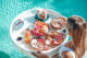 femme tenant petit-déjeuner flottant piscine